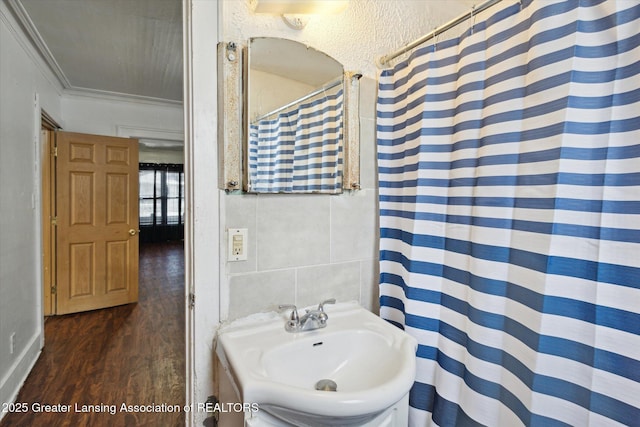 full bathroom with curtained shower, wood finished floors, a sink, tile walls, and ornamental molding