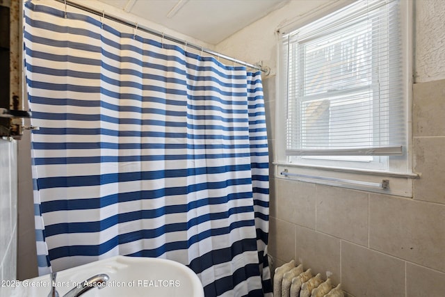 full bathroom featuring curtained shower, radiator heating unit, and tile walls