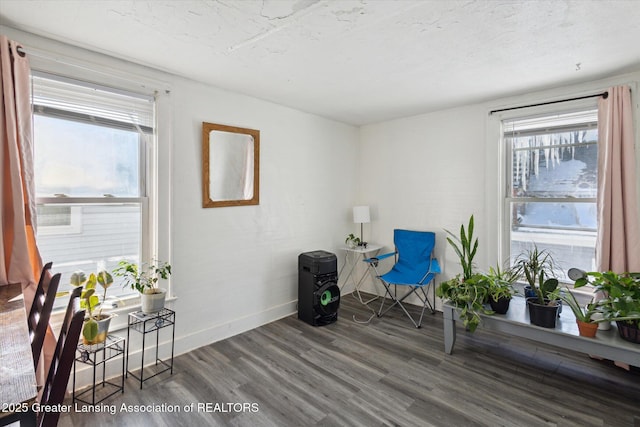 living area featuring a textured ceiling, dark wood-style flooring, and baseboards