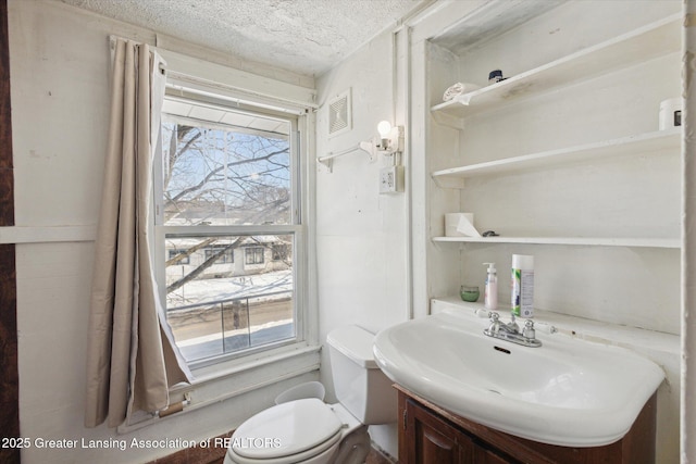 half bathroom featuring a textured ceiling, visible vents, vanity, and toilet