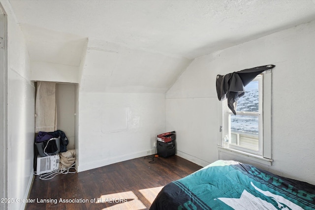 bedroom featuring lofted ceiling, dark wood-style floors, baseboards, and a textured ceiling