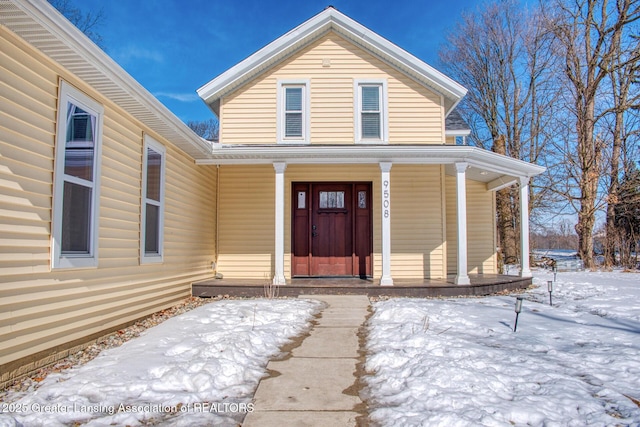 snow covered property entrance featuring a porch