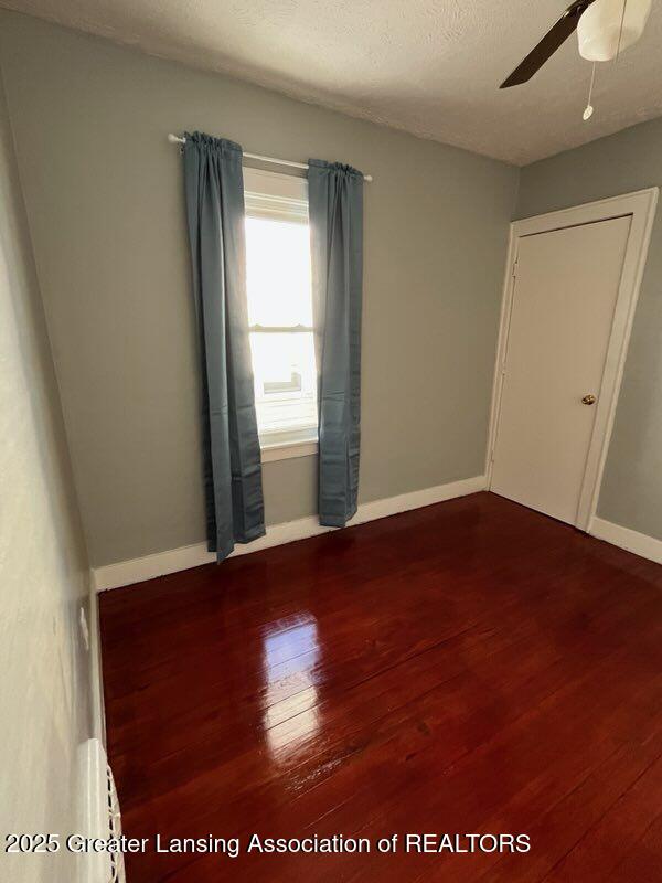 empty room with ceiling fan, baseboards, and wood finished floors