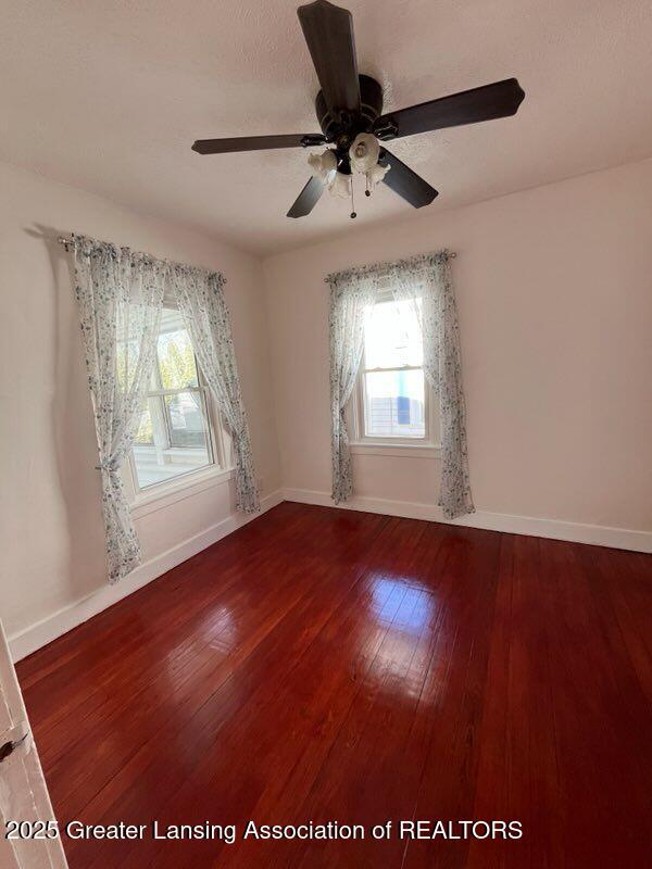 spare room with baseboards and hardwood / wood-style flooring