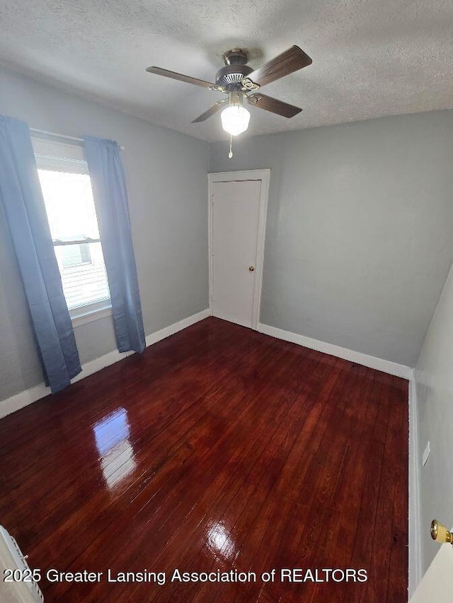 spare room featuring ceiling fan, a textured ceiling, baseboards, and hardwood / wood-style flooring