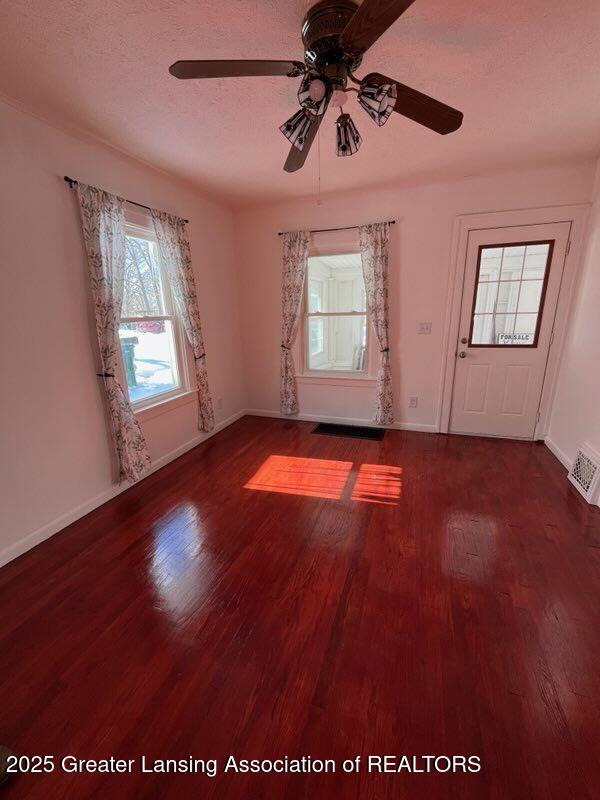 spare room featuring dark wood-type flooring, visible vents, a textured ceiling, and baseboards