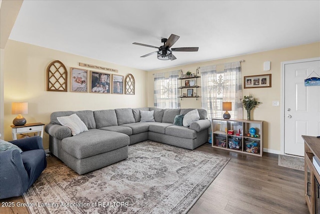 living room with a ceiling fan, baseboards, and wood finished floors