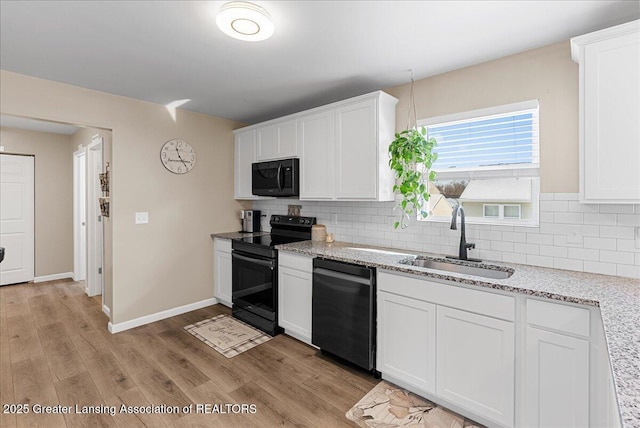 kitchen with decorative backsplash, light wood-style floors, white cabinets, a sink, and black appliances