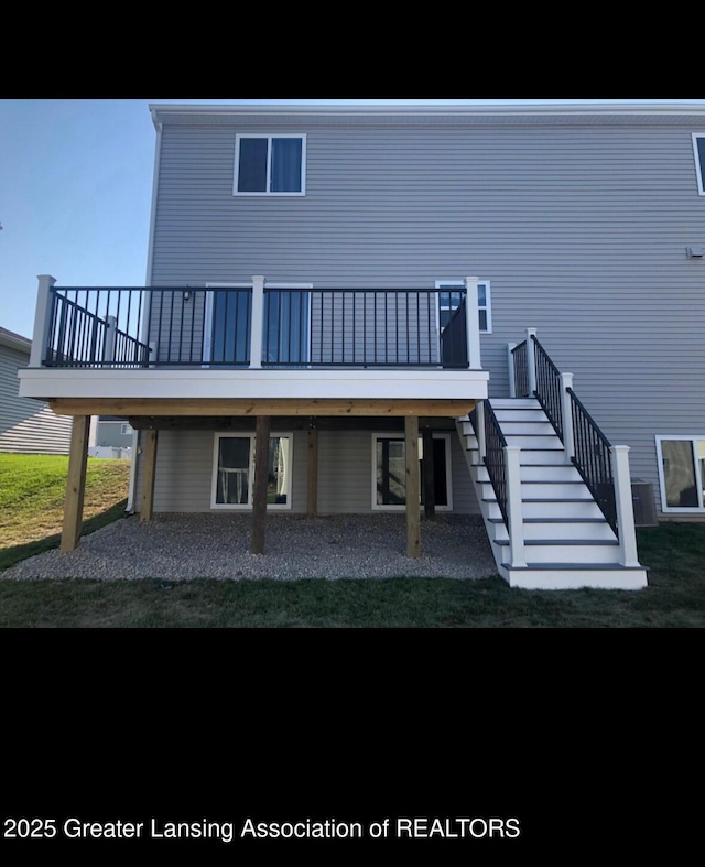 back of property with a deck and stairs