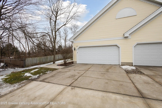 view of side of property featuring driveway, a garage, and fence