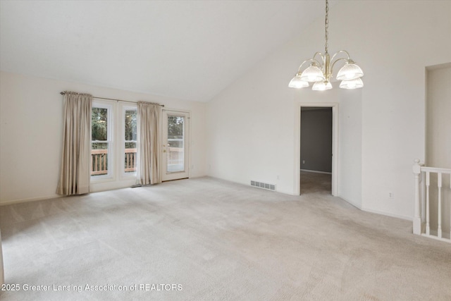 carpeted empty room with high vaulted ceiling, visible vents, and a notable chandelier