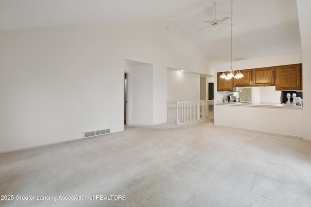 unfurnished living room with light carpet, high vaulted ceiling, visible vents, and ceiling fan with notable chandelier