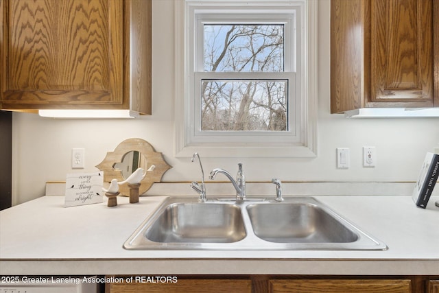 kitchen with brown cabinetry, light countertops, and a sink