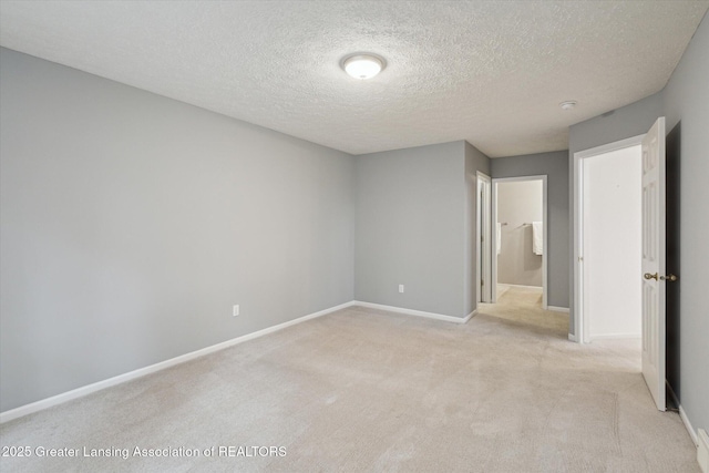 unfurnished bedroom with light colored carpet, a textured ceiling, and baseboards