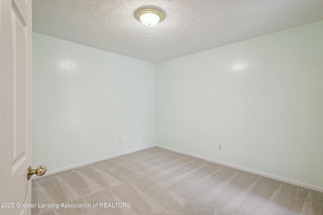 unfurnished room with light carpet, a textured ceiling, and baseboards