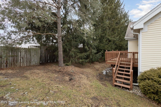 view of yard with fence, a deck, and stairs