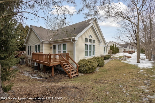 snow covered house featuring roof with shingles, a deck, and central AC unit