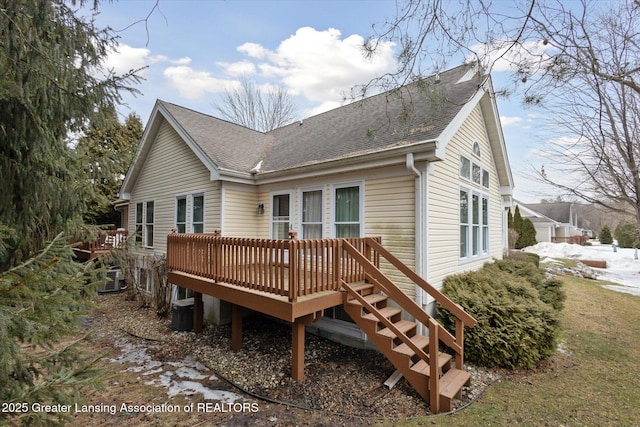 snow covered property with a deck and roof with shingles