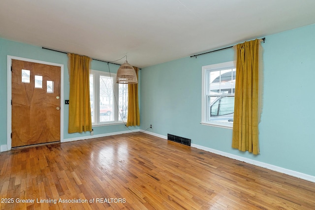 interior space with light wood-type flooring, visible vents, and baseboards