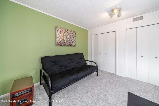 sitting room with a textured ceiling, carpet, and visible vents