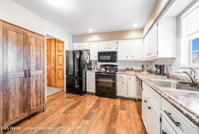 kitchen featuring backsplash, light wood-style floors, white cabinets, a sink, and black appliances