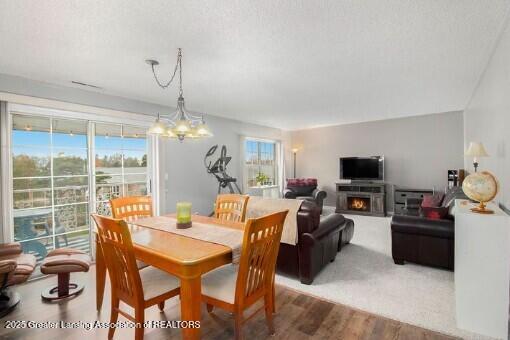 dining space with a warm lit fireplace, wood finished floors, and a chandelier