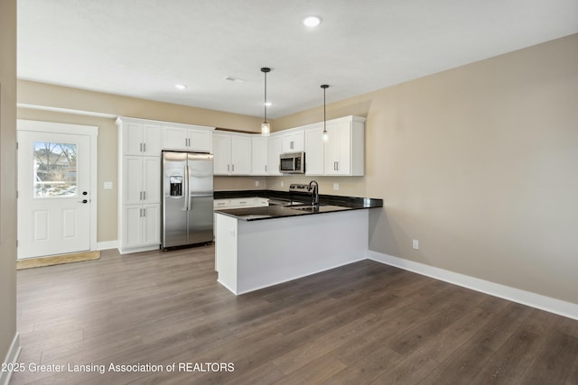 kitchen featuring stainless steel appliances, dark wood-type flooring, a peninsula, and baseboards