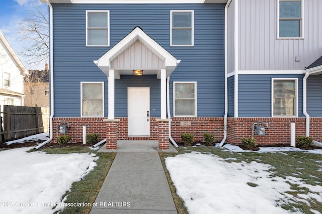 view of front of home with board and batten siding, brick siding, and fence