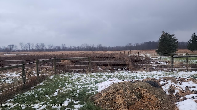 snowy yard with fence and a rural view