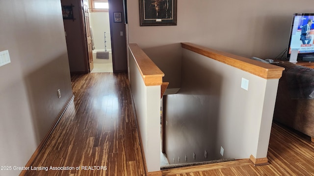 hallway featuring dark wood-type flooring and baseboards