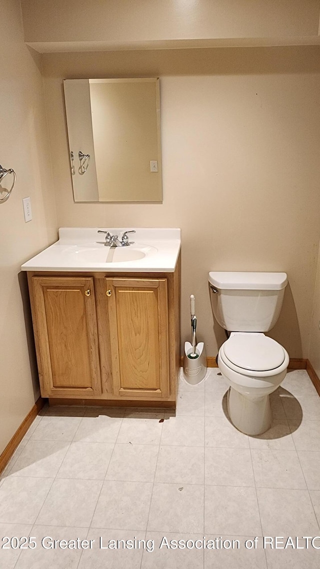 half bath with tile patterned flooring, vanity, toilet, and baseboards