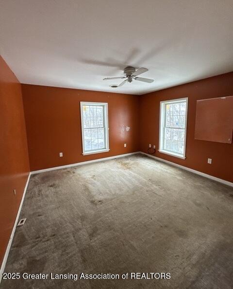 carpeted spare room with ceiling fan and baseboards