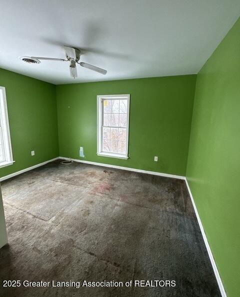 carpeted empty room with a ceiling fan, visible vents, and baseboards