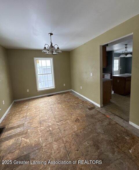 unfurnished dining area featuring baseboards and an inviting chandelier