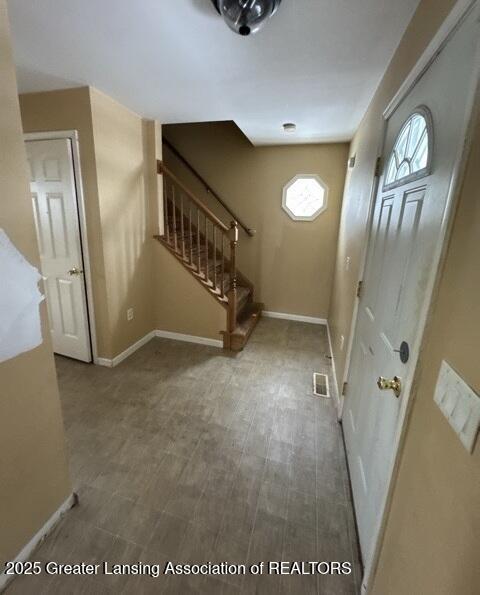 foyer with stairs, visible vents, and baseboards