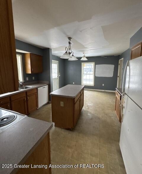 kitchen featuring white appliances, brown cabinets, a wealth of natural light, and a center island