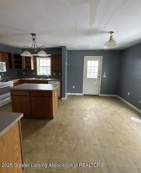 kitchen featuring pendant lighting, stainless steel appliances, a kitchen island, and baseboards