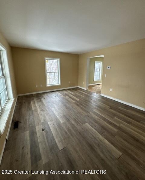 unfurnished room featuring plenty of natural light, wood finished floors, visible vents, and baseboards