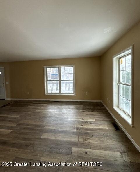 unfurnished room featuring visible vents, baseboards, and wood finished floors