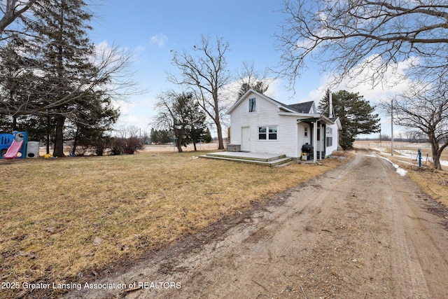 view of home's exterior with dirt driveway, a lawn, and a playground