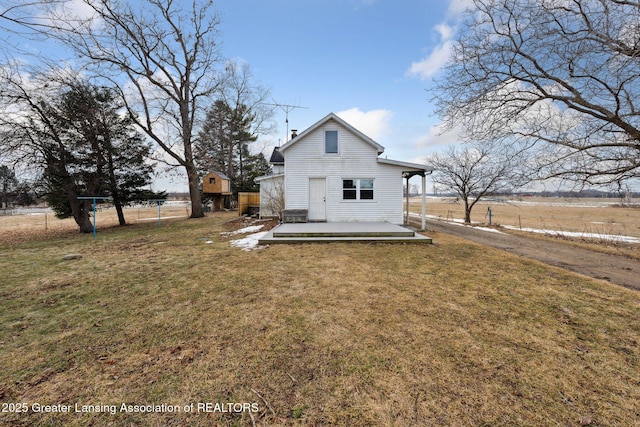 rear view of property featuring a lawn and fence