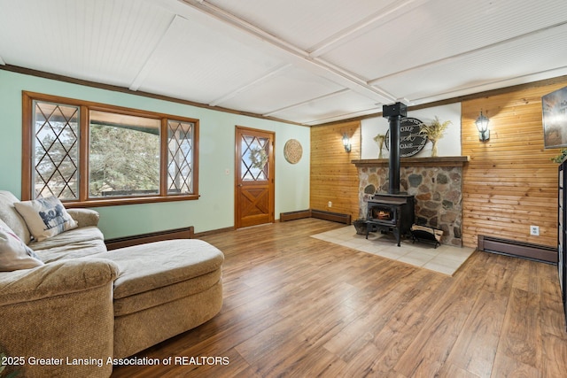 living room with a baseboard heating unit, a baseboard radiator, a wood stove, and wood finished floors