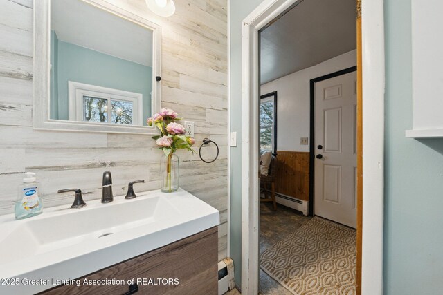 bathroom featuring wood walls, baseboard heating, a wainscoted wall, and vanity