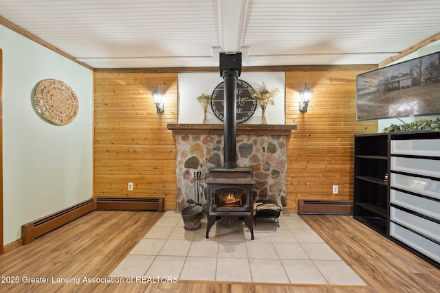 living area featuring baseboard heating, ornamental molding, a wood stove, wood walls, and wood finished floors