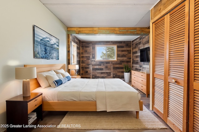 bedroom featuring wood walls, a closet, and wood finished floors