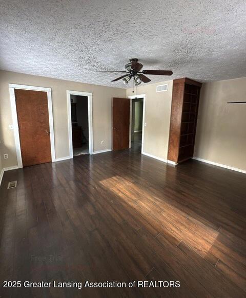 spare room featuring a textured ceiling, ceiling fan, wood finished floors, visible vents, and baseboards