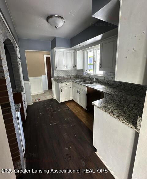 kitchen featuring dark wood finished floors, white cabinetry, decorative backsplash, and a sink