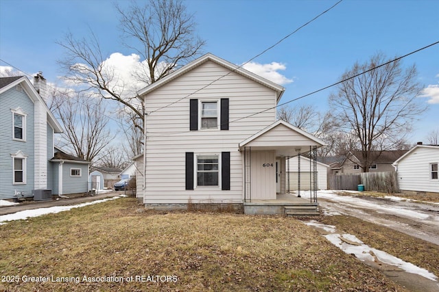 traditional-style home with fence, central AC, and a front yard