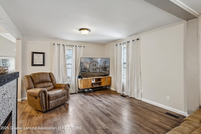 sitting room with plenty of natural light, wood finished floors, visible vents, and baseboards