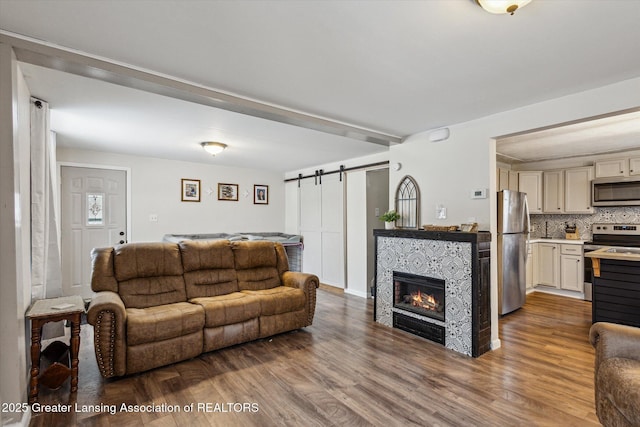 living area with a barn door, wood finished floors, and a tile fireplace